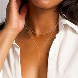 Close-up of a person wearing a delicate silver necklace with a blurred background