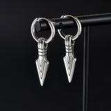 A pair of silver-toned metal hoop earrings with dangling arrowhead charms, displayed on a black jewelry stand against a black background.