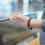 Person's arm with a bracelet holding onto a railing indoors