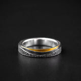 Silver ring with a gold accent on a black background